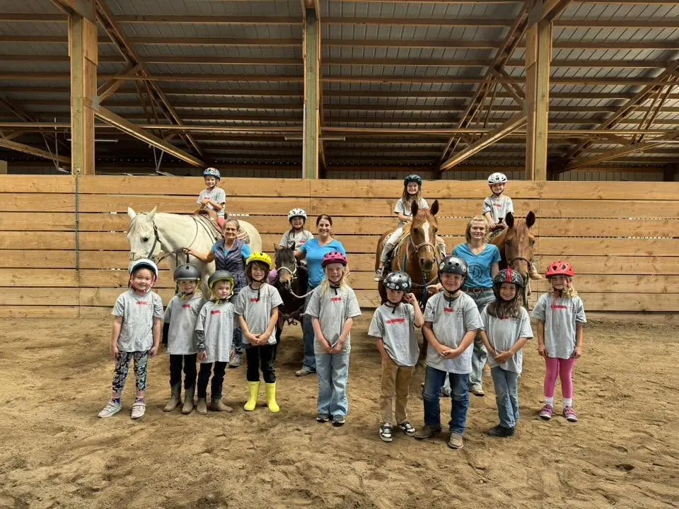 Kids in matching shirts with their horses and ponies in the arena