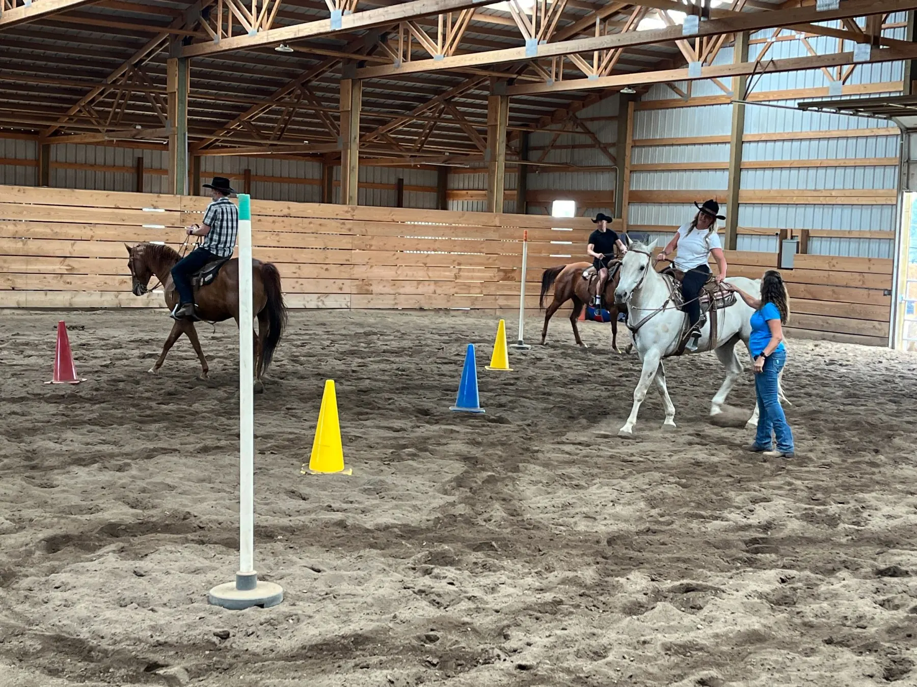 Tanya coaching riders through a pole drill in the indoor arena