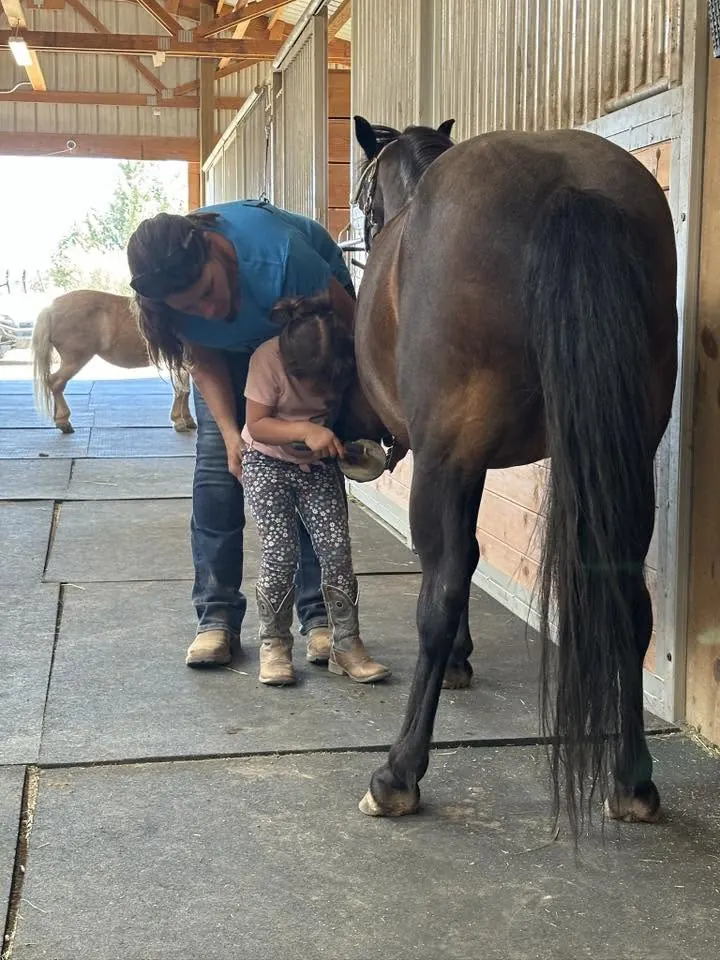 Tanya teaching a young student to pick a hoof