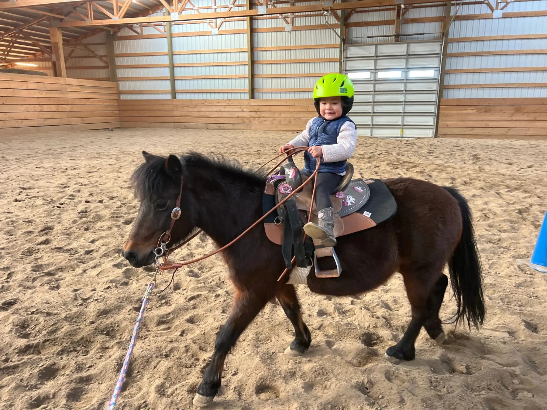 A young rider in a helmet on a pony